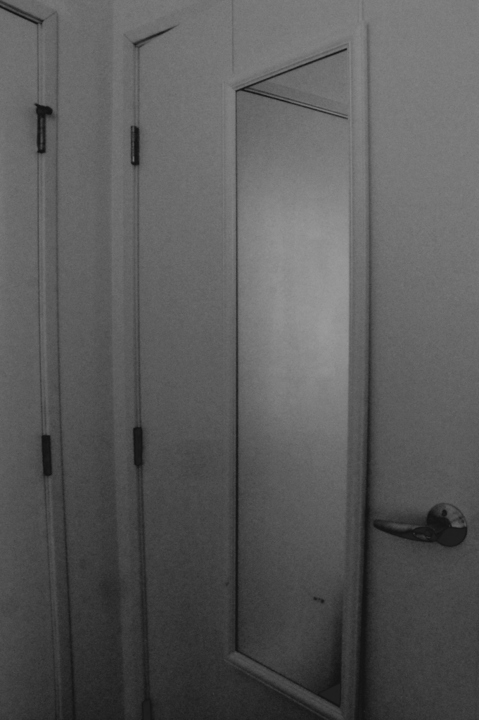 Black and white image of an over the door mirror.